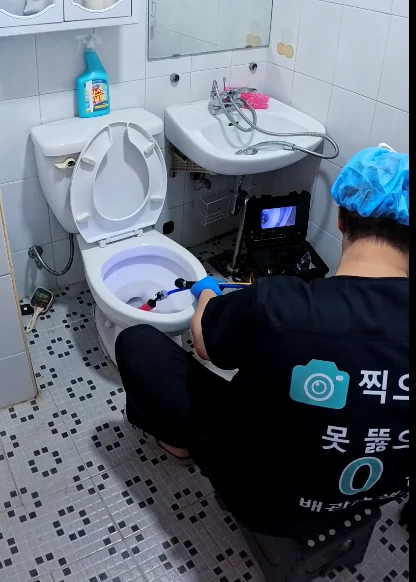 변기 앞에서 화면을 보며 내부를 점검하는 보관 사진